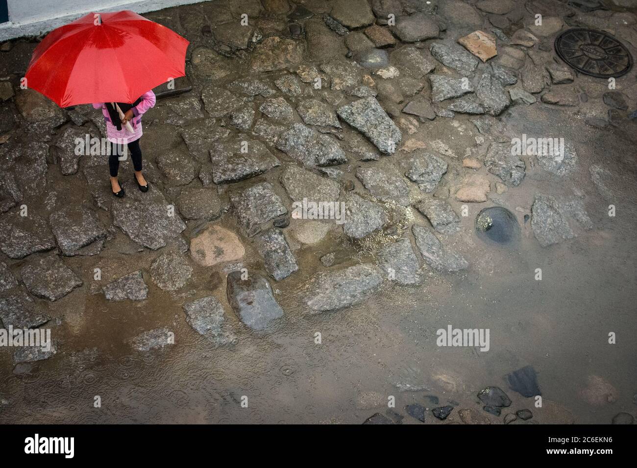 Girl with his umbrela in the middle of an old street Stock Photo