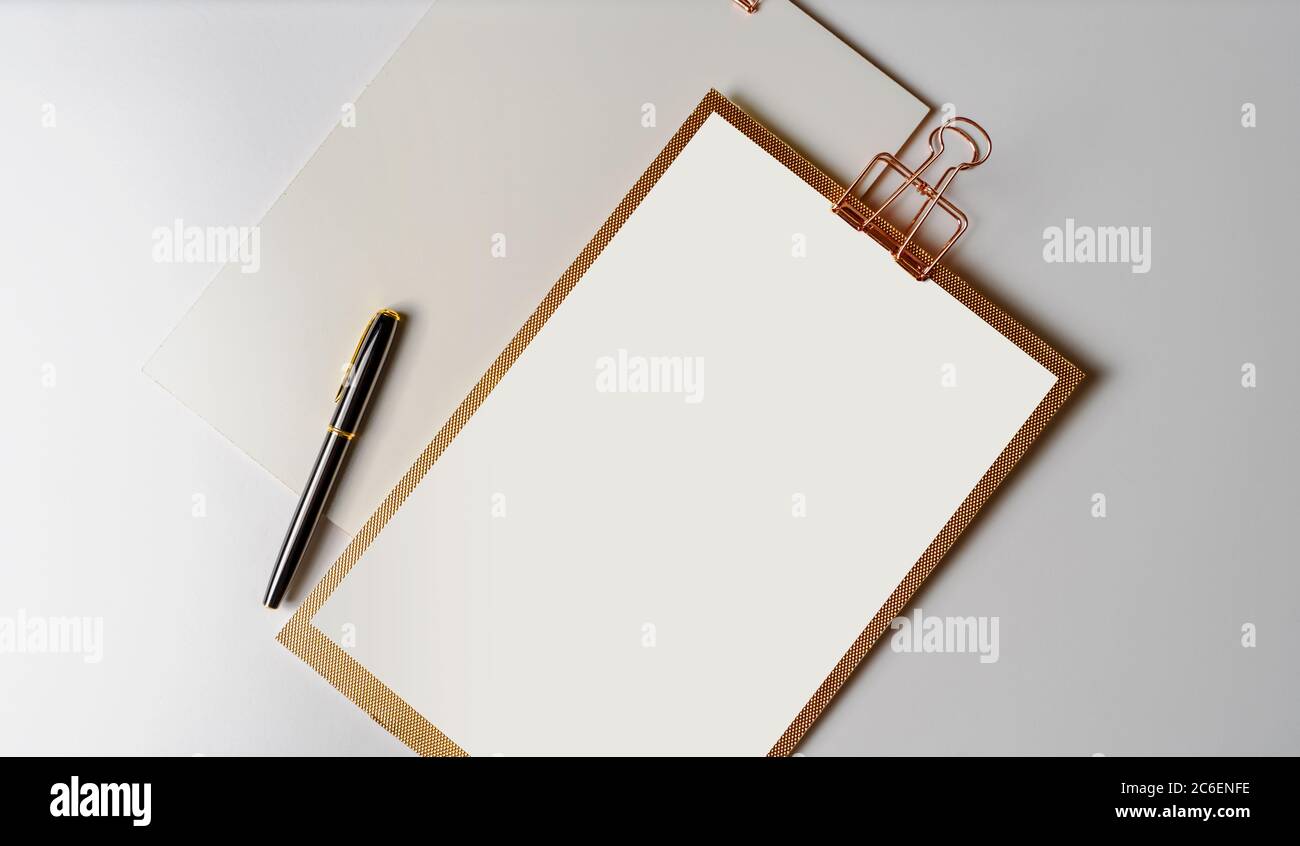 Clipboard with golden clip, blank sheets of paper and pen on white background. Template for branding identity. minimal mock up template concept. Stock Photo