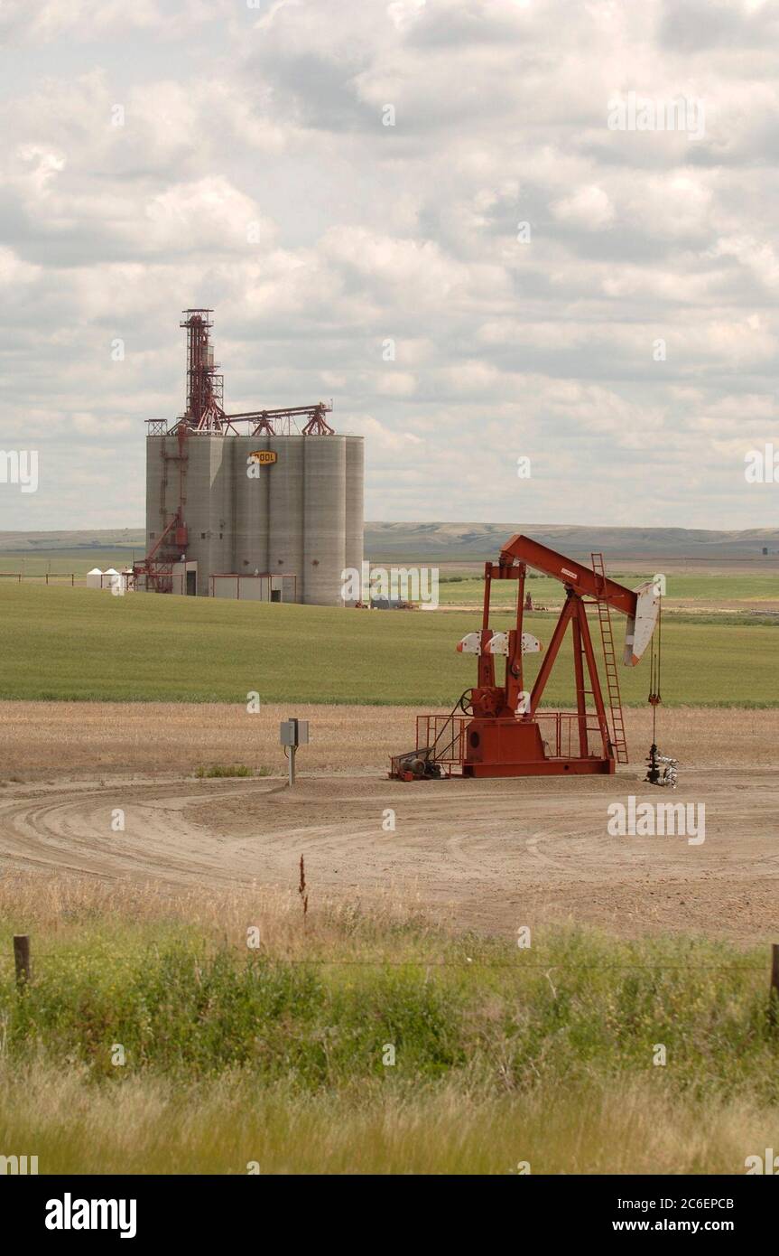 Southern Saskatchewan, Canada  July 25, 2005: Oil pumpjack and grain elevator along the Trans-Canada Highway in southwestern Saskatchewan. ©Bob Daemmrich Stock Photo