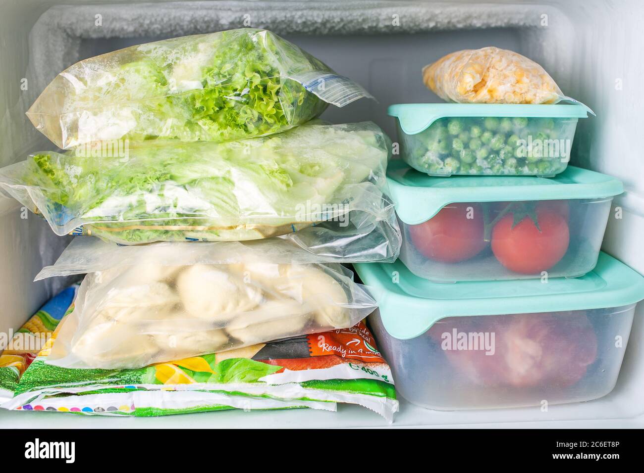 Frozen vegetables and meat in blue plastic containers. Frozen yellow