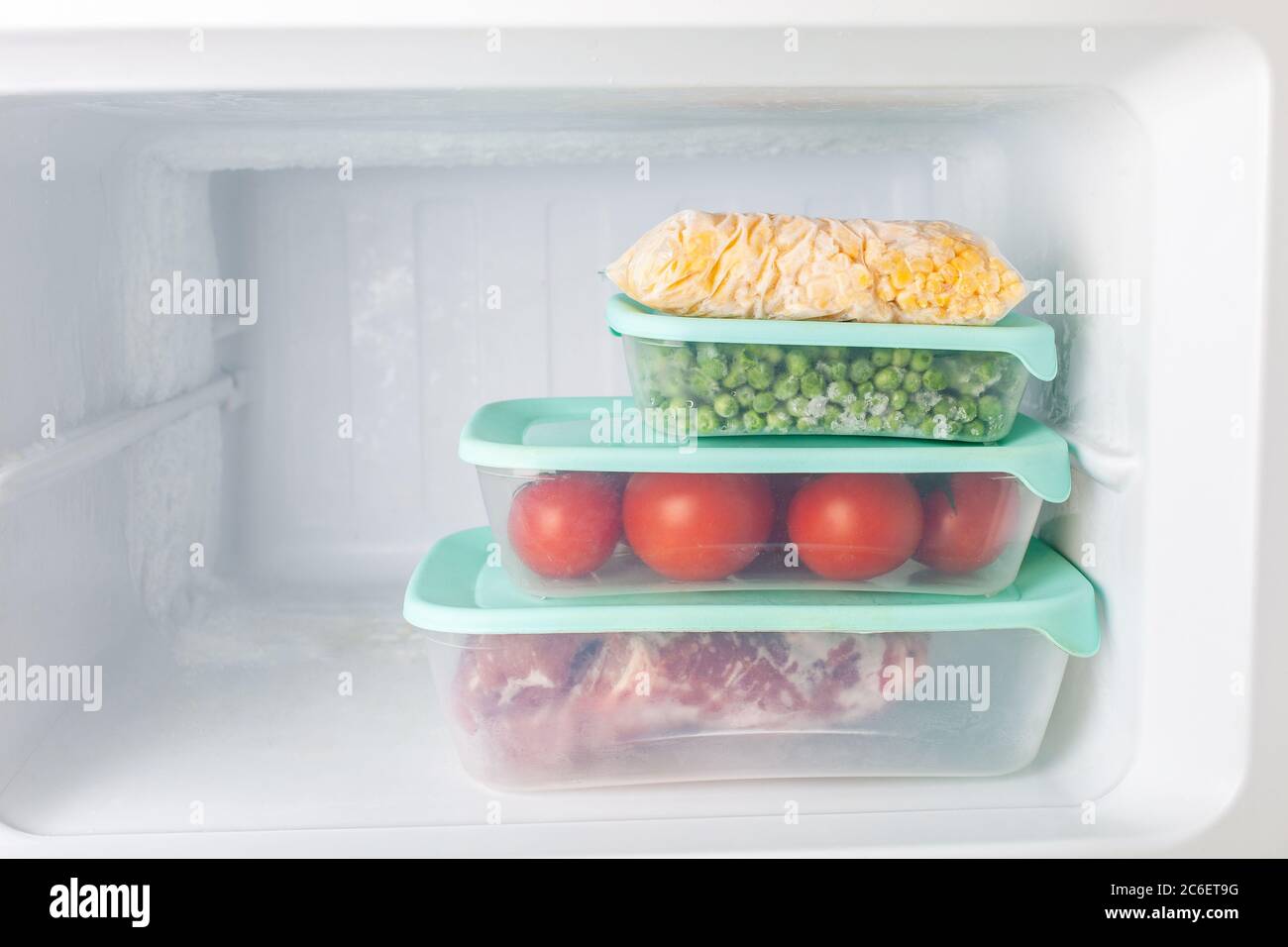 Frozen vegetables and meat in blue plastic containers. Frozen corn