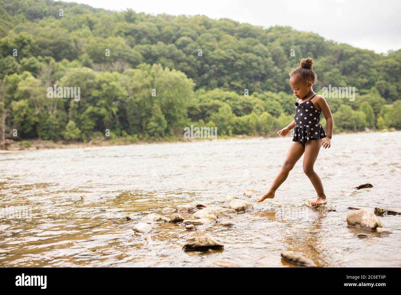 A young mixed race girl wades in the shallow water of the Shenandoah River at Harpers Ferry, West Virginia, USA. Stock Photo