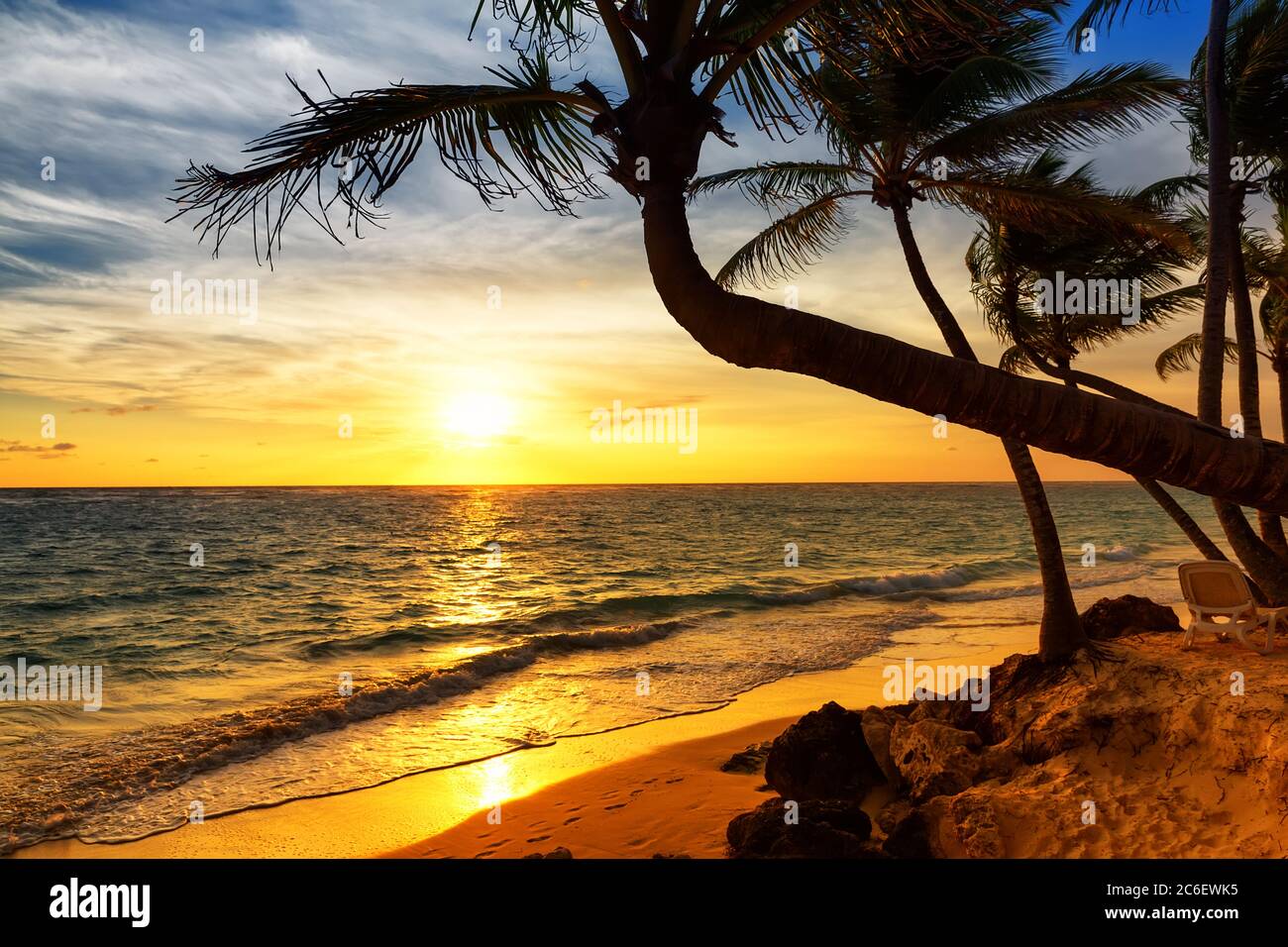 Palm trees silhouette on sunset tropical beach. Coconut palm trees against colorful sunset on the beach in Punta Cana, Dominican Republic. Stock Photo