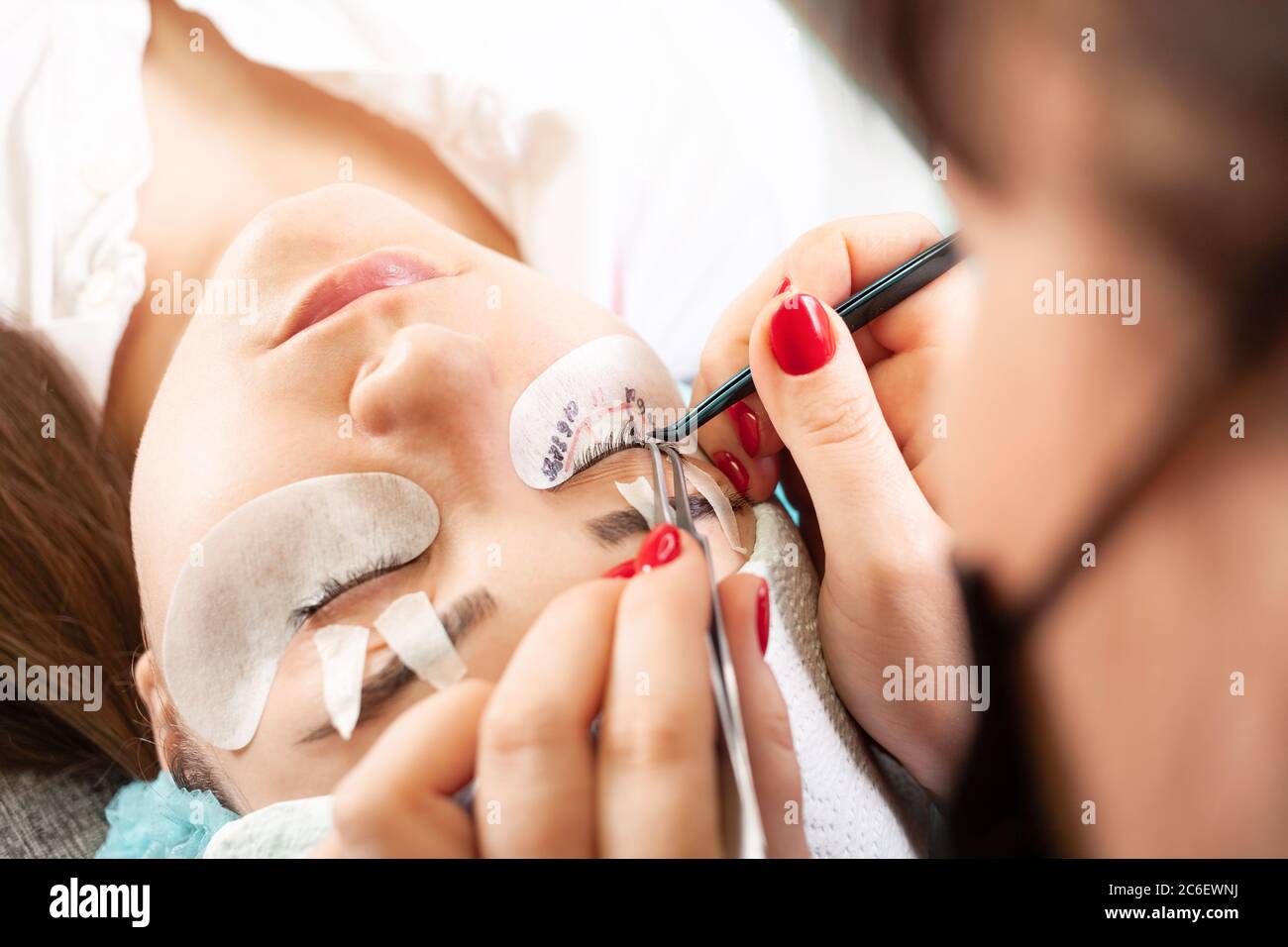 Eyelash extensions in a beauty salon. A young girl lies on a couch with