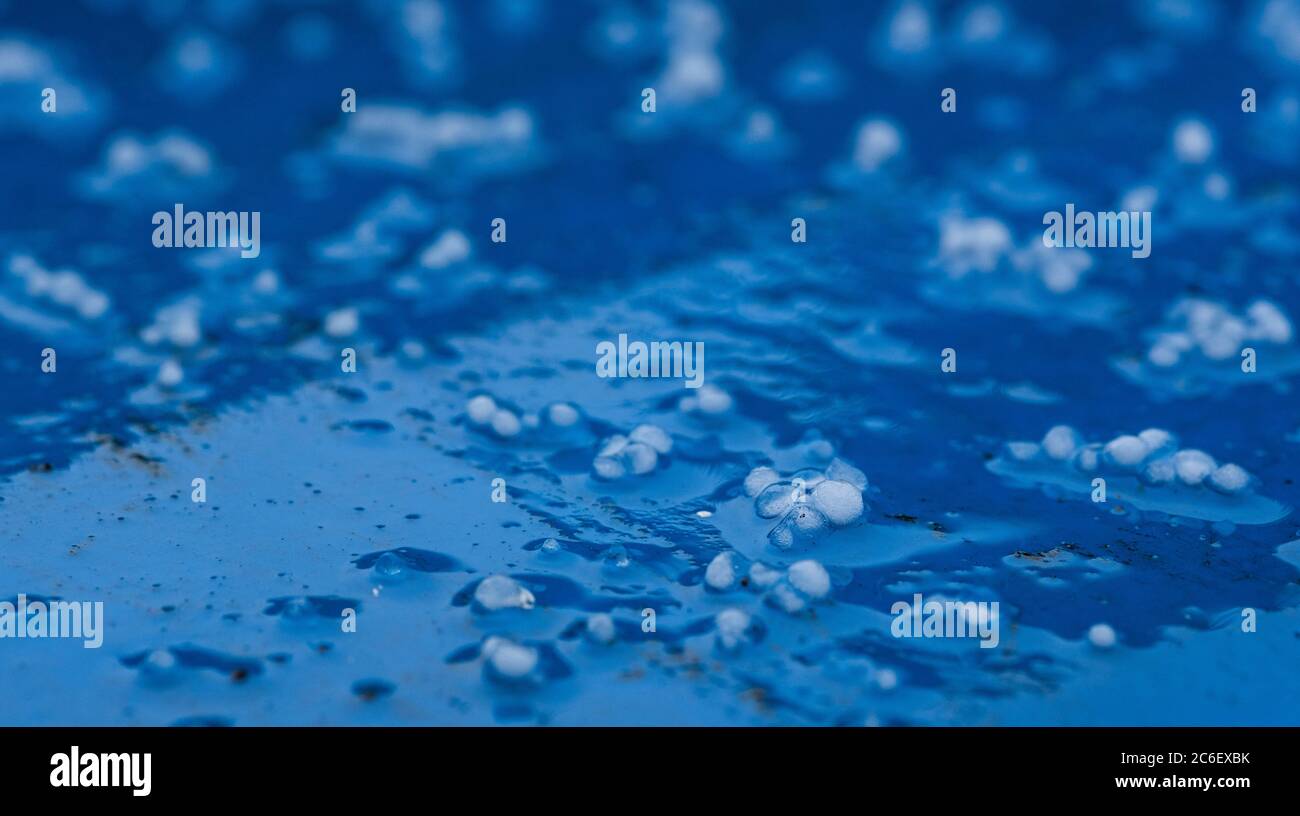 Hailstones capturing black particulates of pollution from the atmosphere above London on a bright blue background. Stock Photo