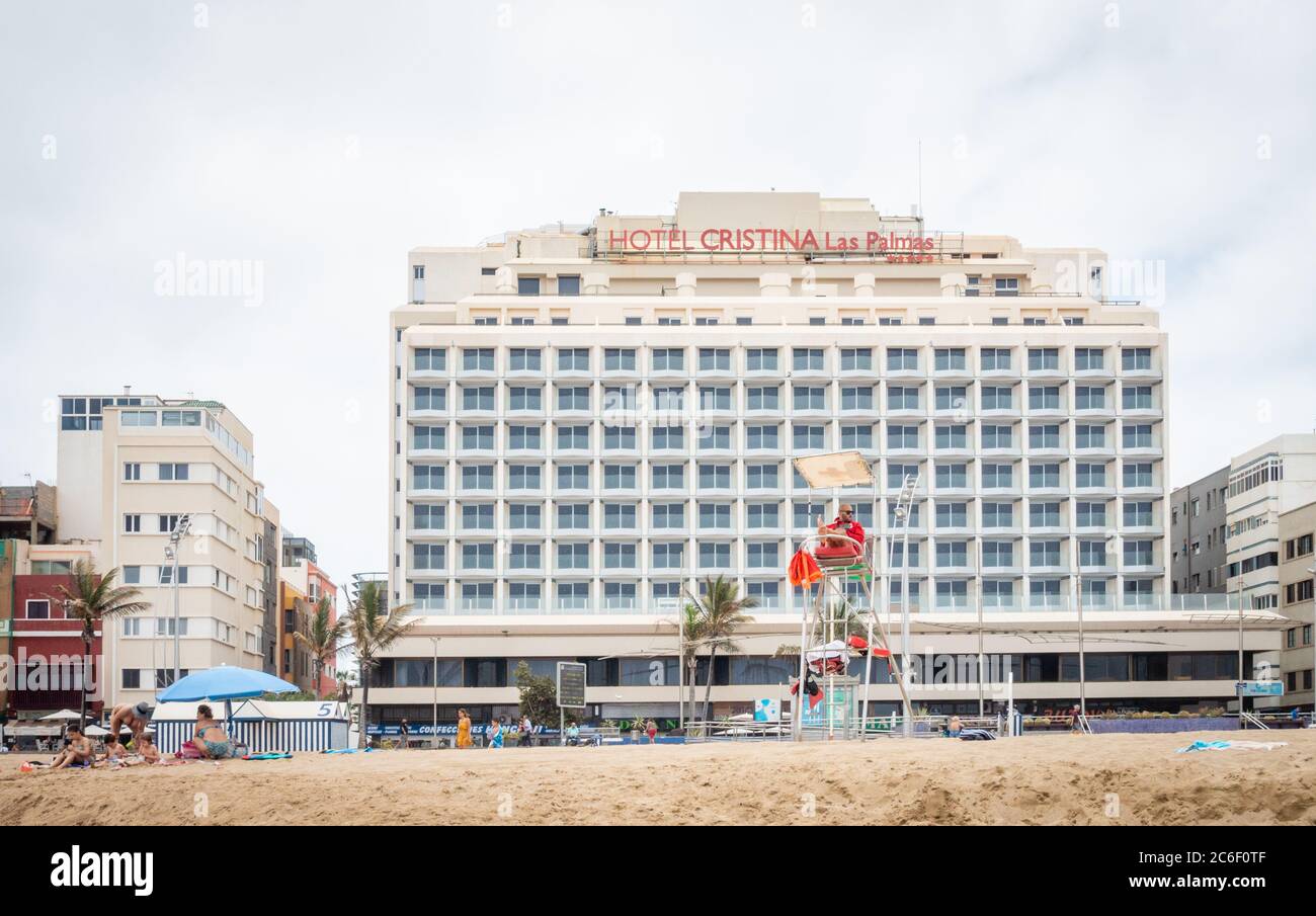 Las Palmas, Gran Canaria, Canary Islands, Spain. 9th July, 2020. A  lifeguard looks out over an almost tourist free city beach in Las Palmas on Gran  Canaria with the closed 4 star