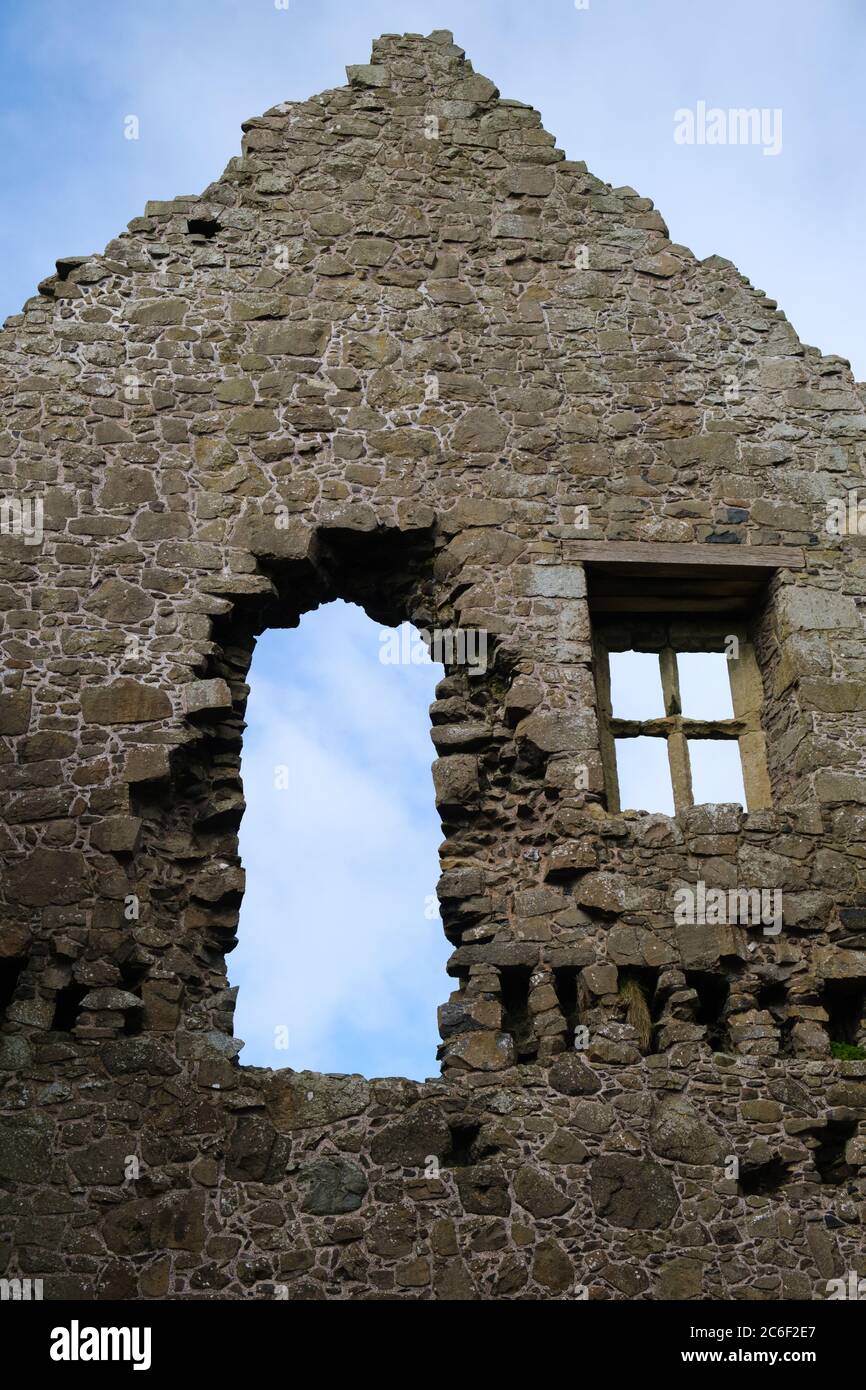 Blue sky and fluffy light cloud visible through the old windows of the ancient ruins at Dunluce Castle in County Antrim, Northern Ireland Stock Photo