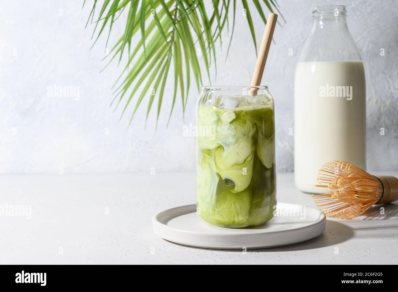 Iced Green matcha tea mixed with ice cube and milk in latte glass on white. Stock Photo