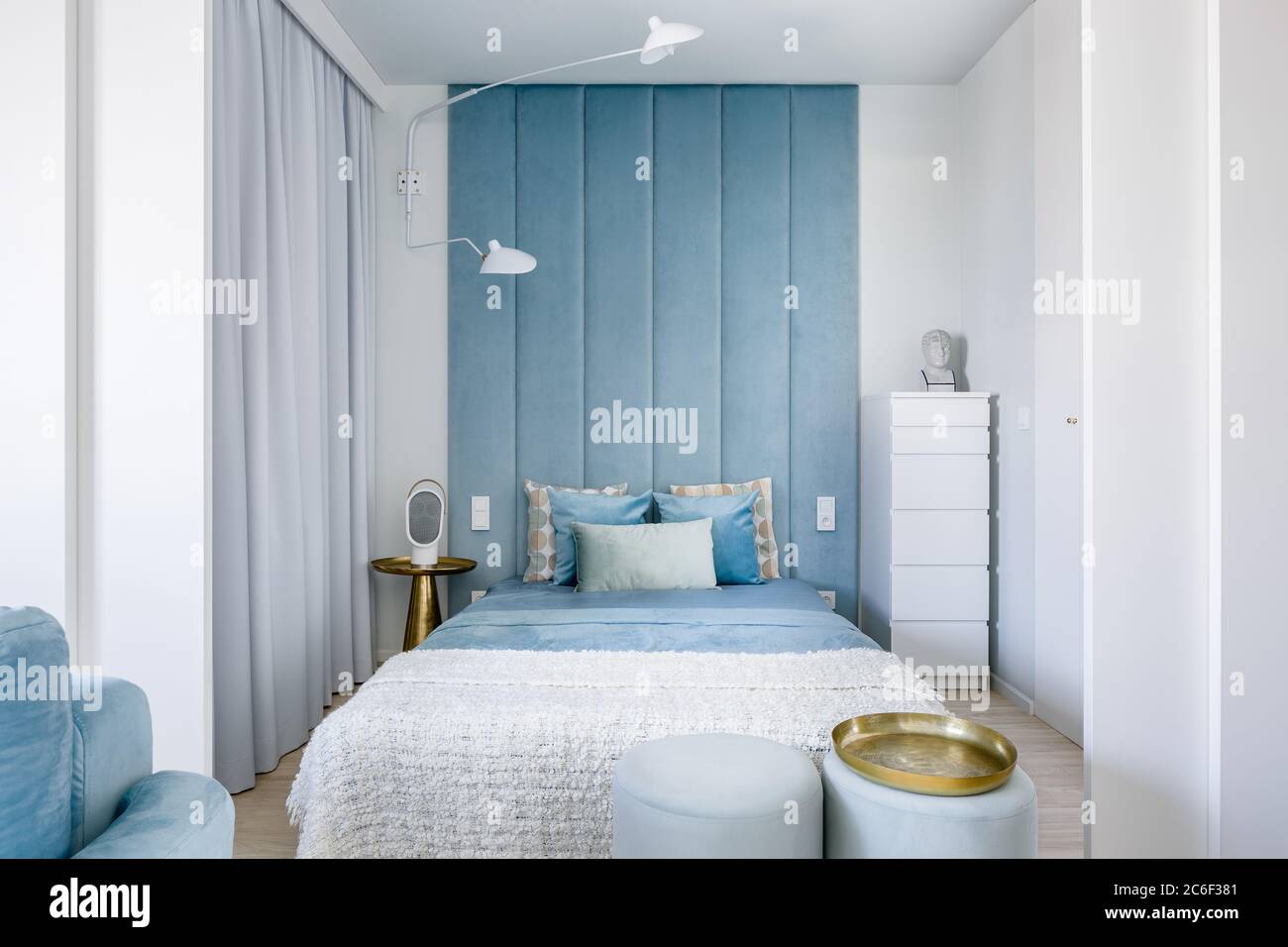 Narrow blue and gray bedroom with double bed and upholstered wall Stock Photo
