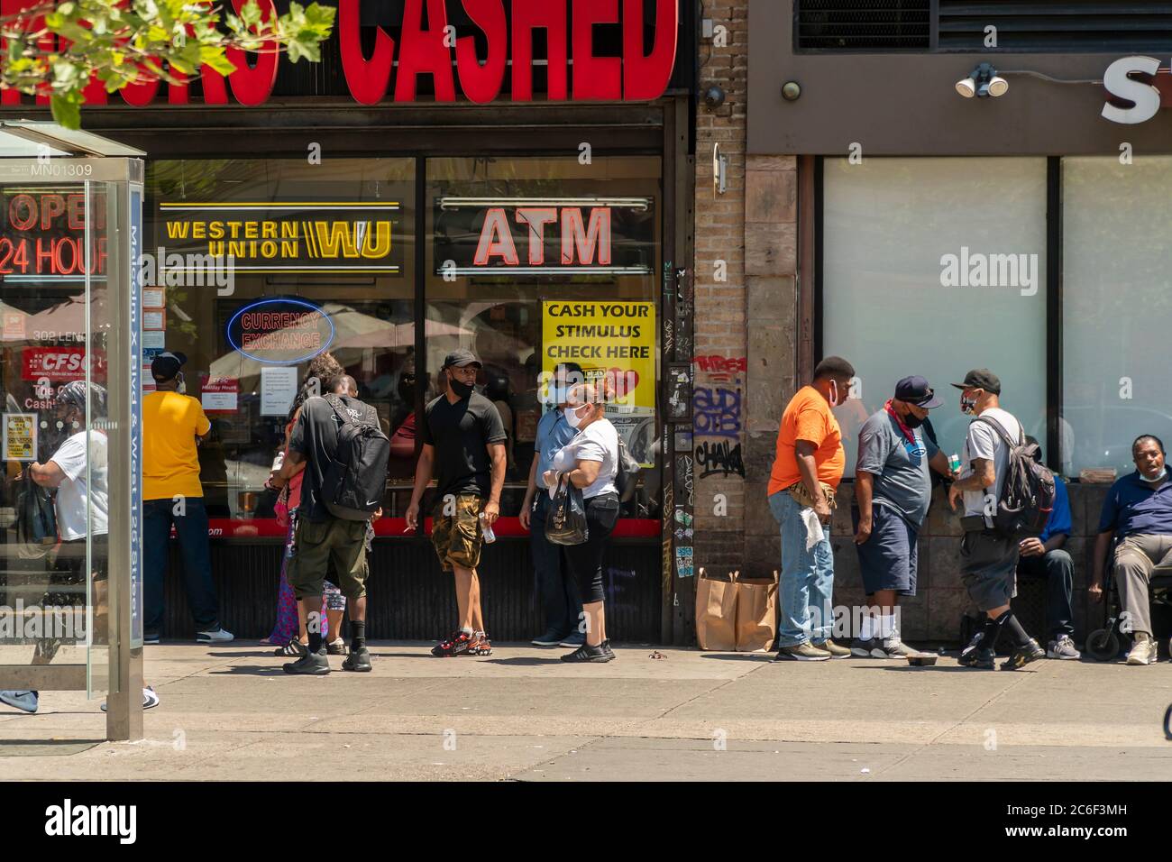 Customers line up outside a check cashing business in Harlem in New York on Saturday, July 4, 2020 that advertises that they cash stimulus checks. (© Richard B. Levine) Stock Photo