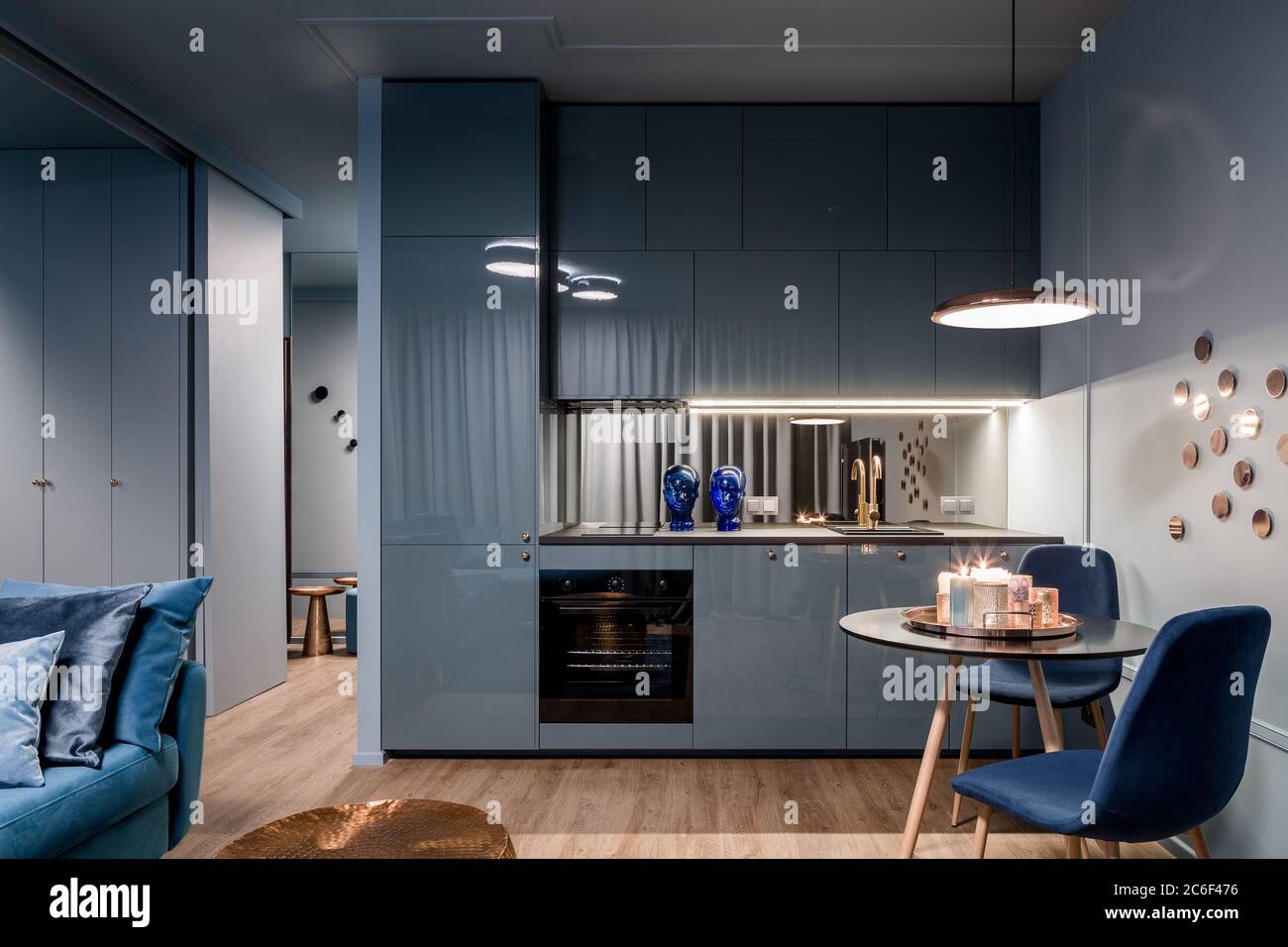 Dark home interior in blue with open kitchen and dining area with round table Stock Photo