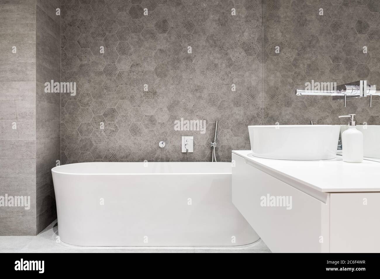 Contemporary bathroom with white bathtub, oval washbasin and hexagonal tiles Stock Photo