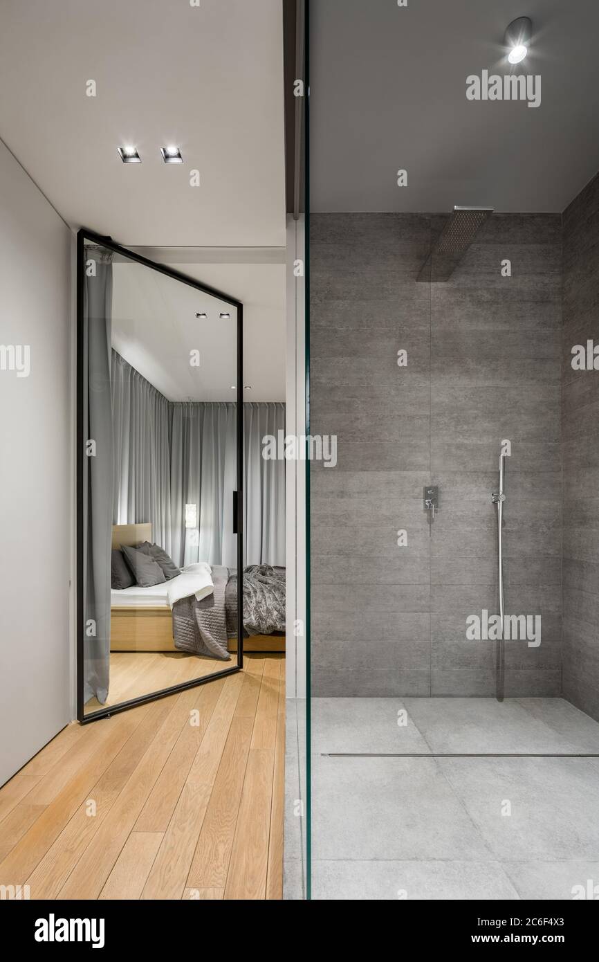 Modern bathroom with spacious walk in shower next to bedroom with glass door Stock Photo