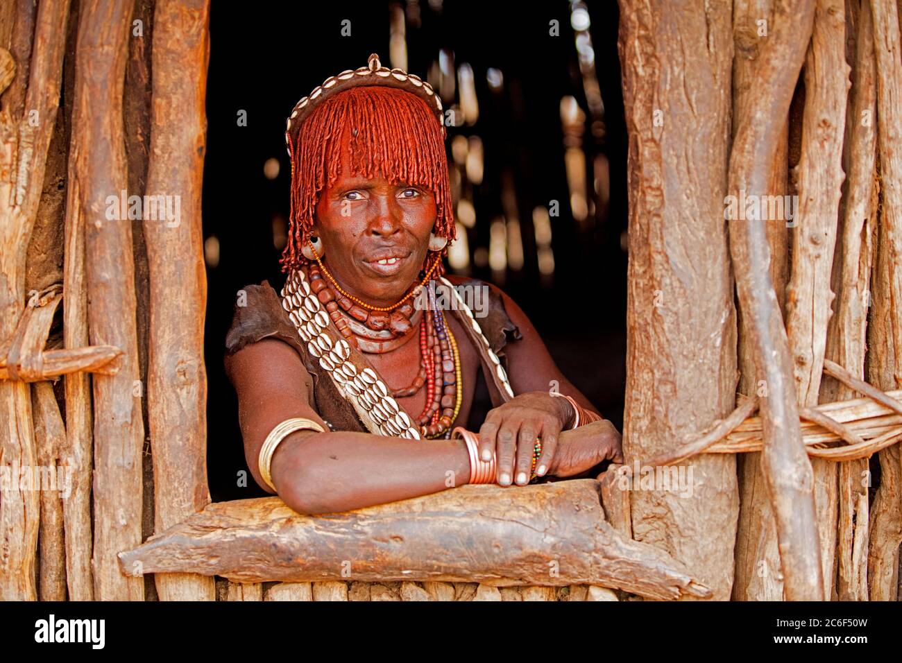 Old black woman of the Hamar / Hamer tribe looking through window in village in the Omo River valley, Debub Omo Zone, Southern Ethiopia, Africa Stock Photo