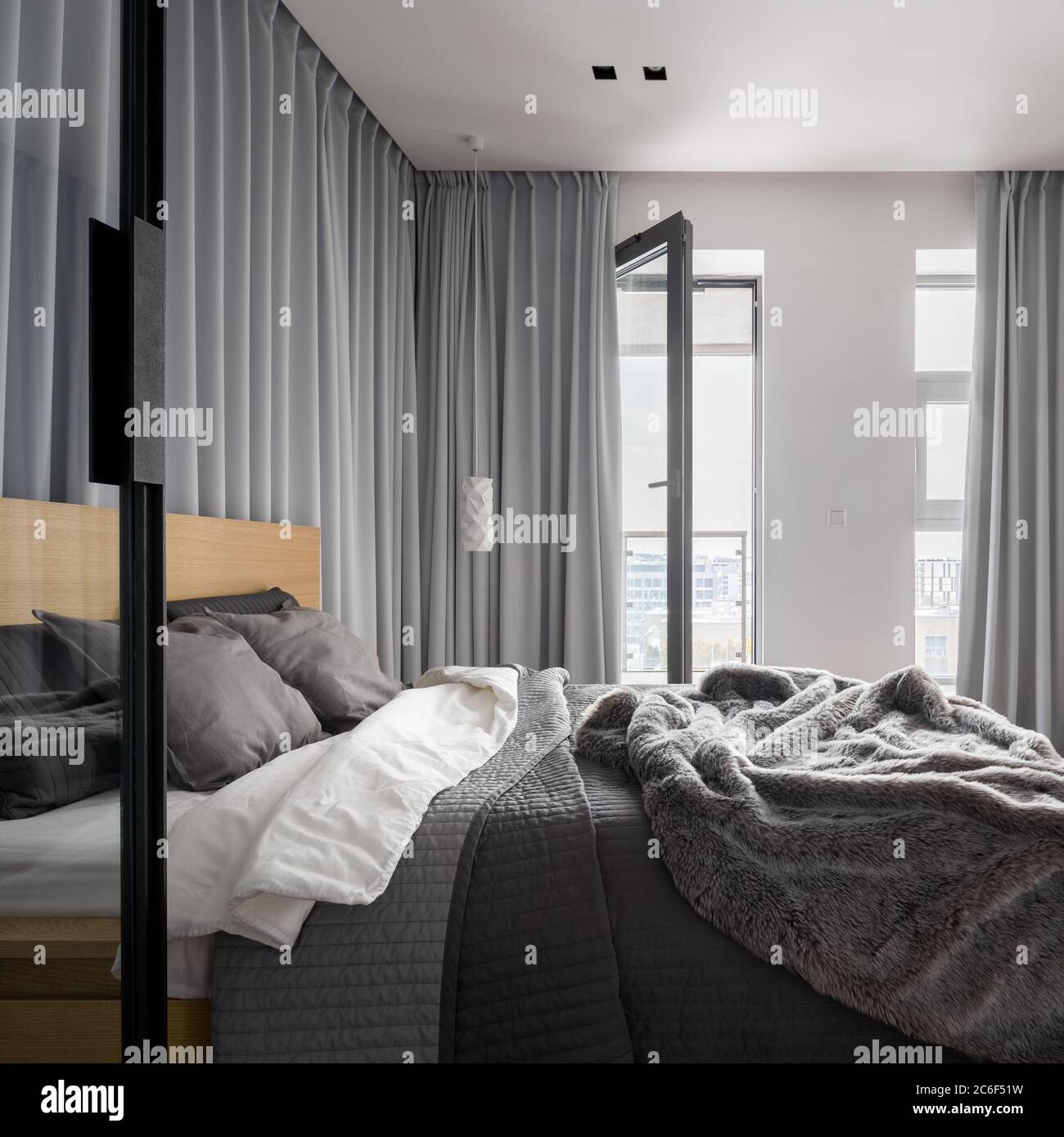 Luxurious bedroom with double bed and gray window curtains Stock Photo