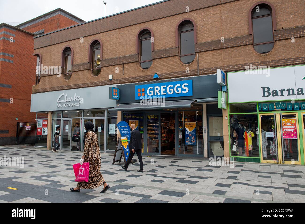 Slough, Berkshire, UK. 9th July, 2020. A lady wears a facemask and leopard  print sari together with a face mask as she does her shopping in Slough  High Street. Credit: Maureen McLean/Alamy