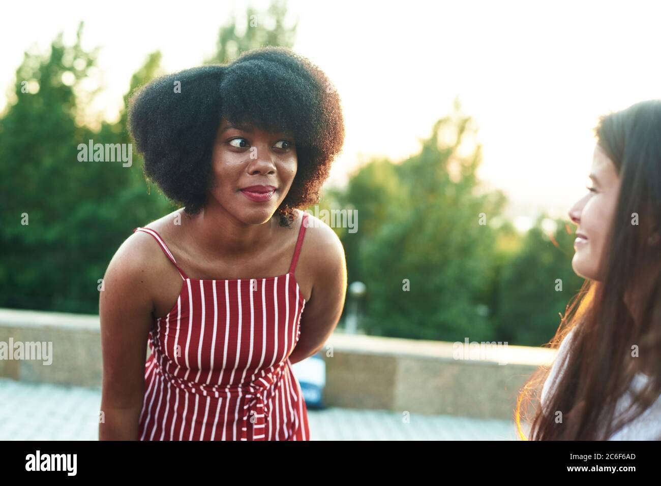 Astonished black girl listens to gossip from her friend. Stock Photo
