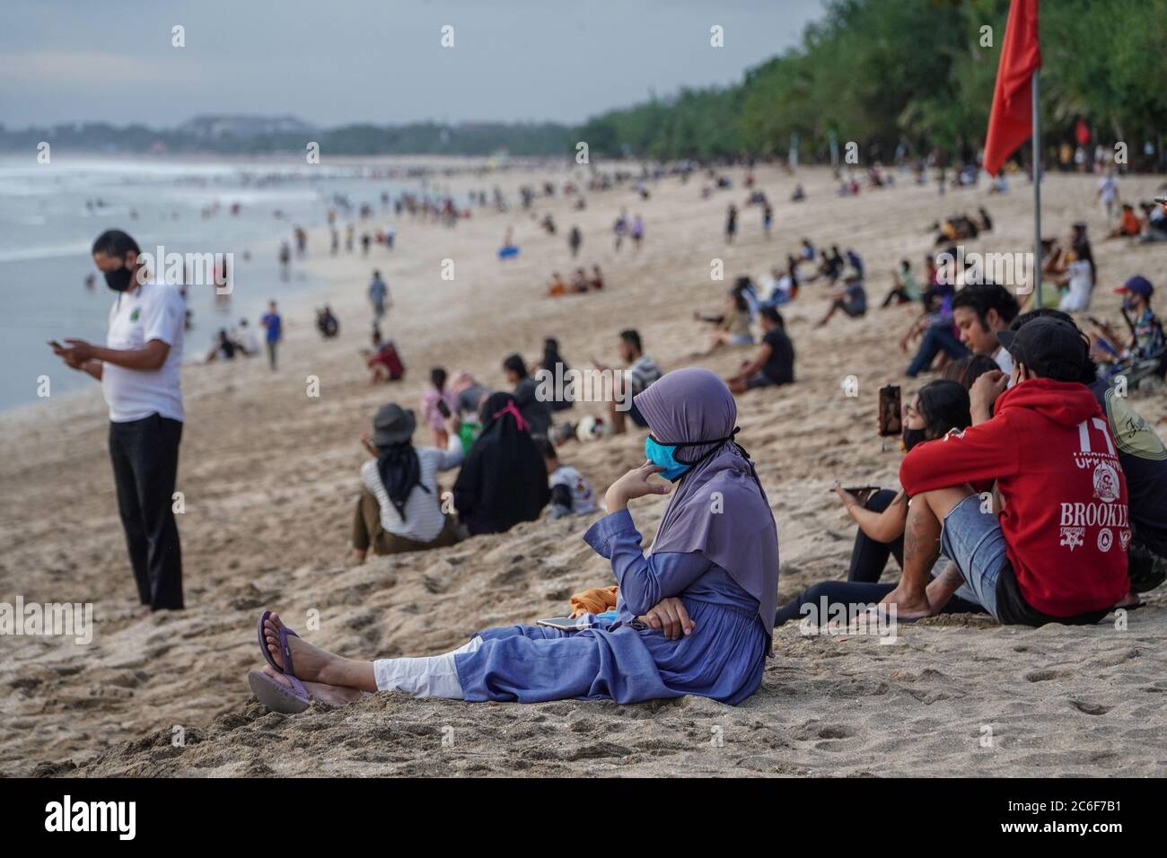 Badung, Bali, Indonesia. 9th July, 2020. People flocks in Kuta Beach await for sunset time. Local government start reopen famous tourism icon of Beach for Bali citizens stage