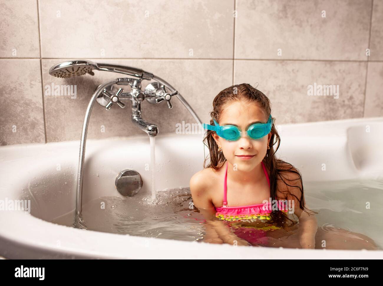 Portrait of a charming caucasian funny little girl in a swimsuit and