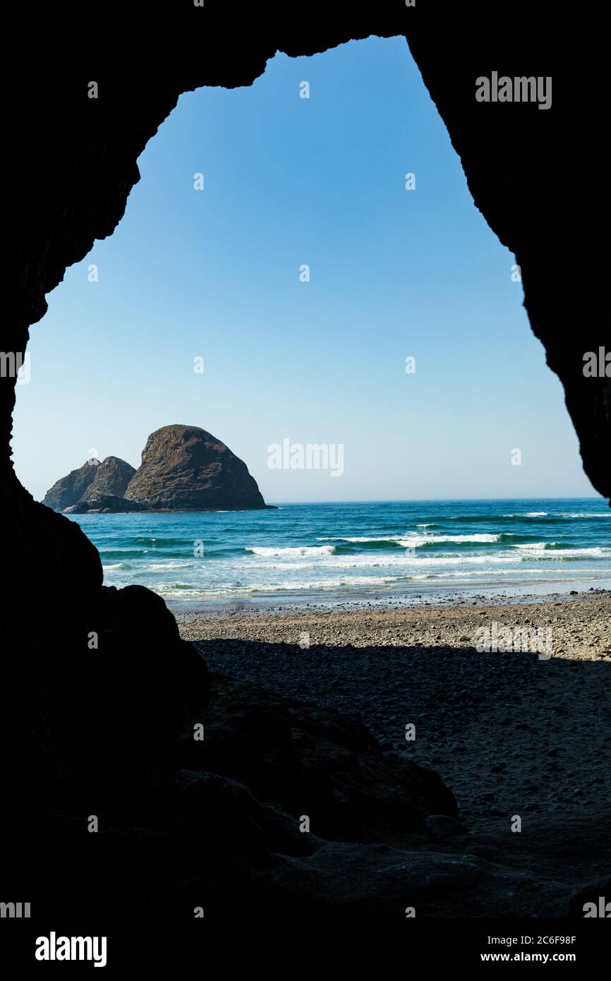 Vertical Image - Cave exit frames view of Sea Stacks along beach near Oceanside Oregon Stock Photo