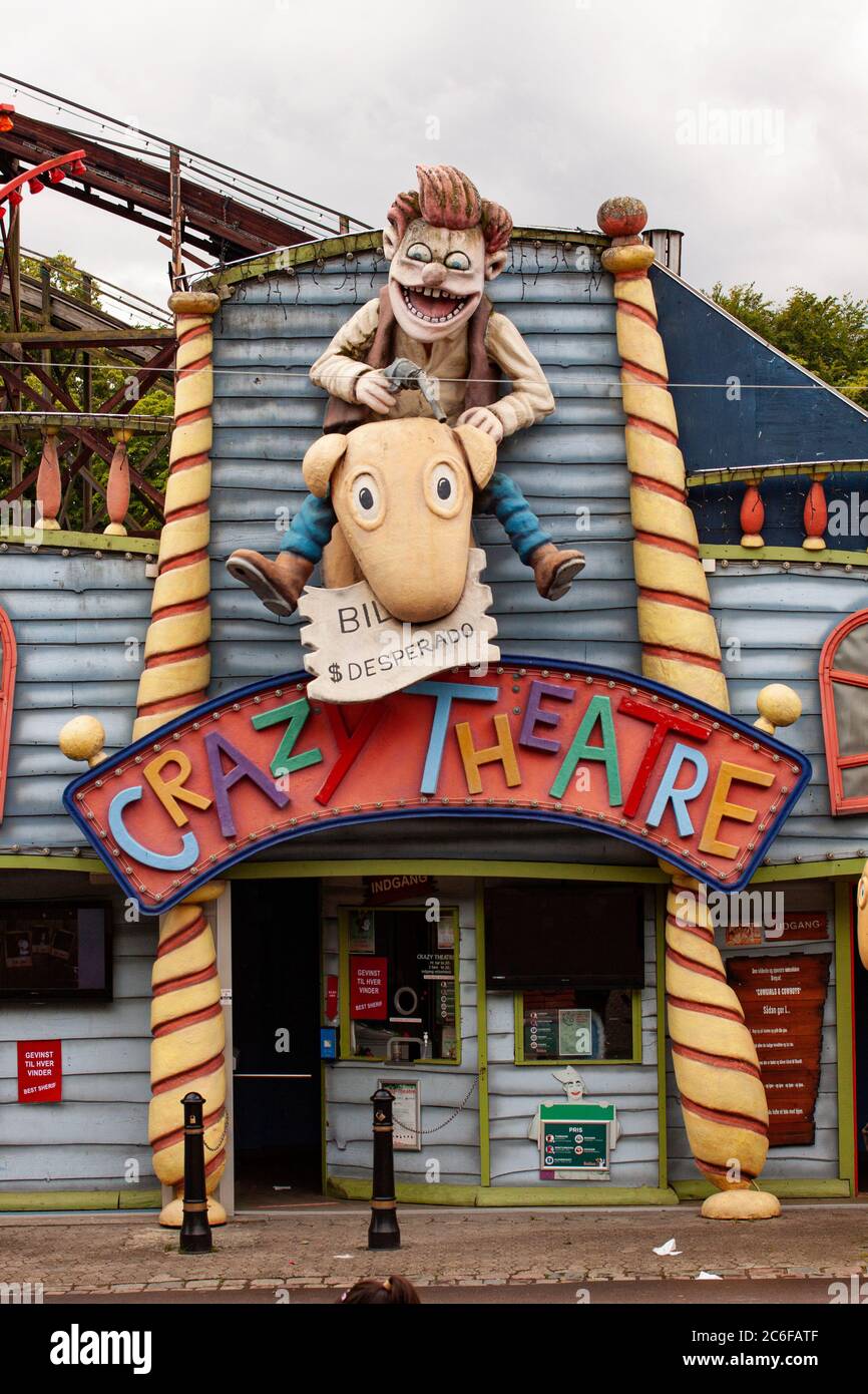 Funny wooden cowboy with pistol and horse figure at amusement park on building facade. Entrance to a Crazy Theatre. Copenhagen, Denmark - July 7, 2020 Stock Photo