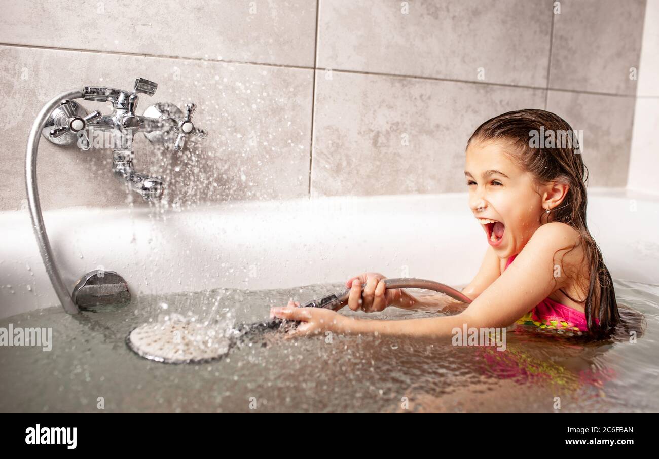 Emotional funny caucasian girl joyfully plays with water pouring from