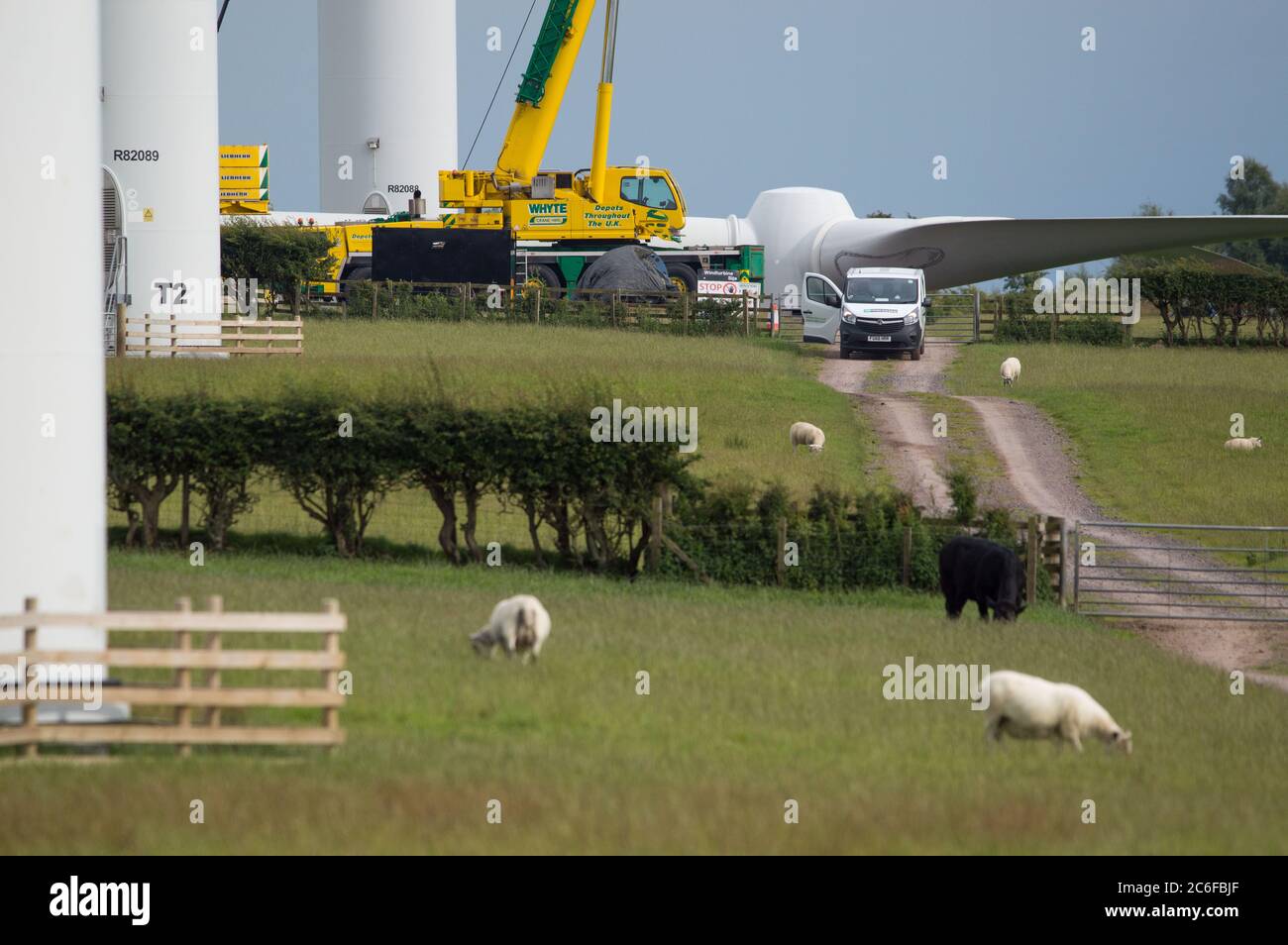 Larkhall, Scotland, UK. 9th July, 2020. Pictured: A huge wind turbine stands a few hundred feet tall whilst its blades lay on the ground ready to be attached. Green energy is is big business, and if the UK is to archive its targets for renewable energy then more wind turbines onshore and offshore need to be built. Credit: Colin Fisher/Alamy Live News Stock Photo