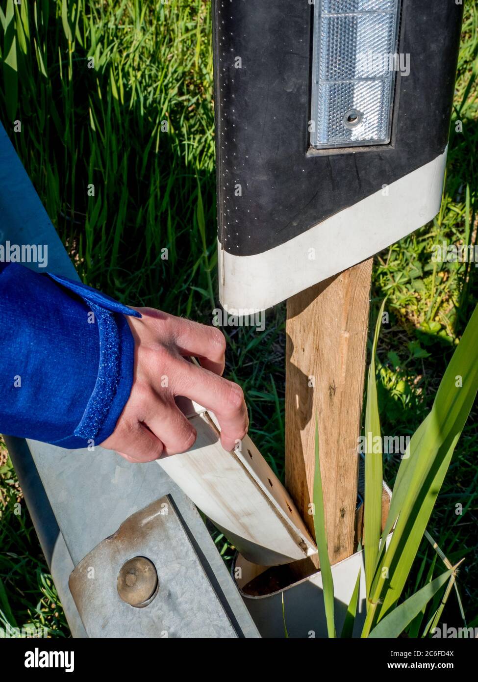 a geocacher puts the geocache back into the hiding place inside a ...