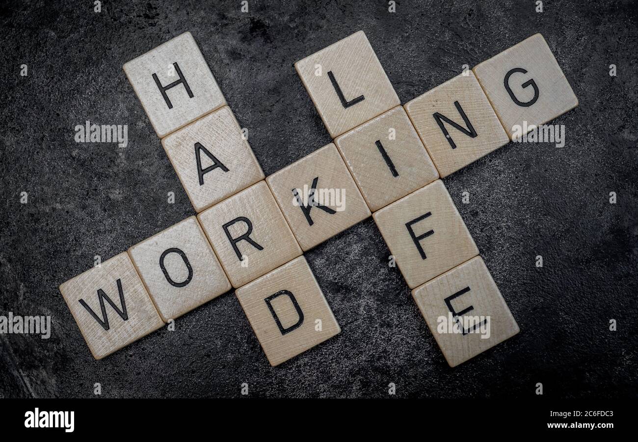 wooden letter tiles forming words on a grey cast iron surface in the background, working hard life Stock Photo