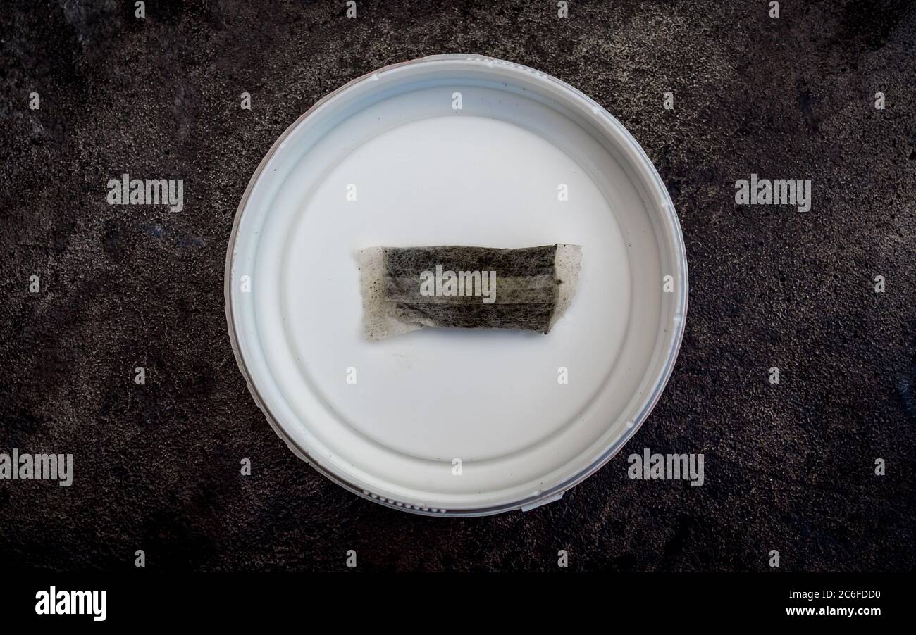 one pouch of swedish chewing tobacco snus is left over in a white round box isolated on grey cast iron surface Stock Photo