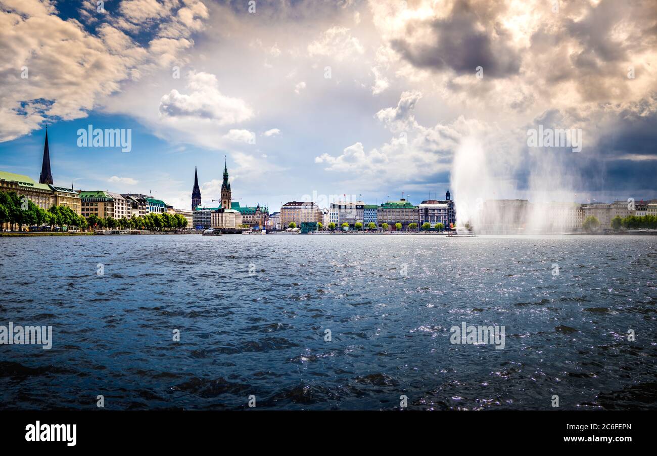 idyllic horizontal panorama of the binnenalster waterfront in hamburg old town with view to the jungfernstieg with town hall and majestic church tower Stock Photo