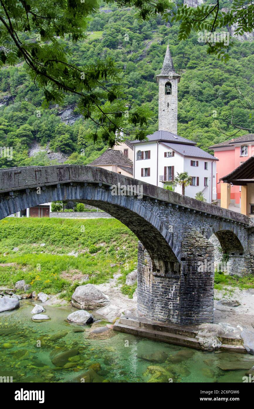 Bignasco village with San Rocco church and the ancient stone brige over the Maggia River in Valley Lavizzara, Ticino, Switzerland Stock Photo
