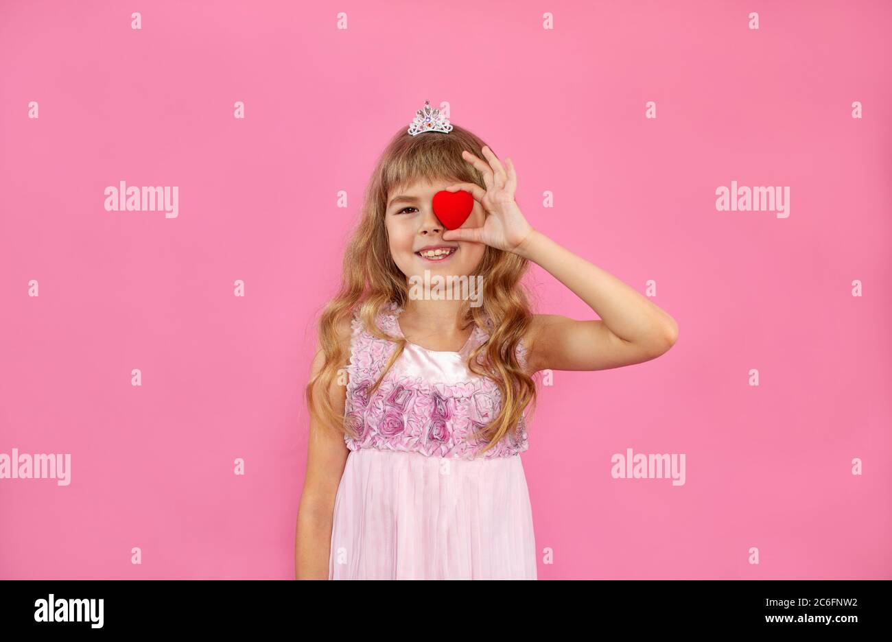 Little girl on a pink background. Little girl with a heart in her hands ...
