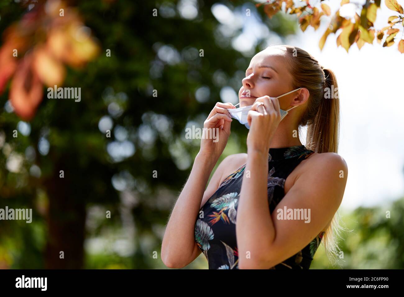 Girl exercising outdoors taking inhaling fresh air from wearing her mask Stock Photo
