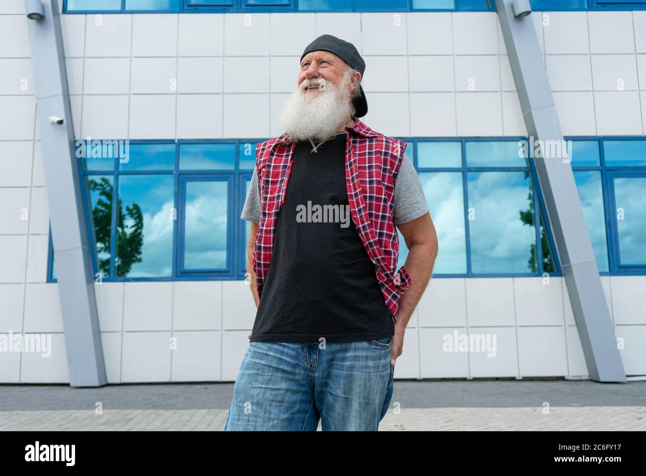 Experienced senior old man with beard on street posing and smiling, portrait Stock Photo