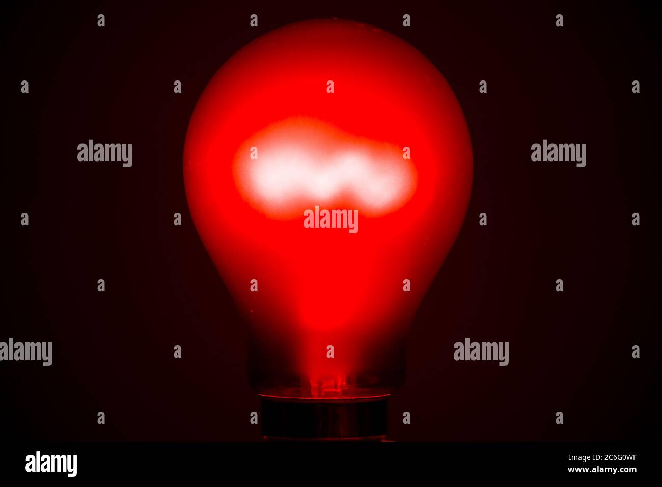 Crompton ruby red tungsten incandescent filament lightbulb lit, red bulb, lightbulb, light, lamp Stock Photo