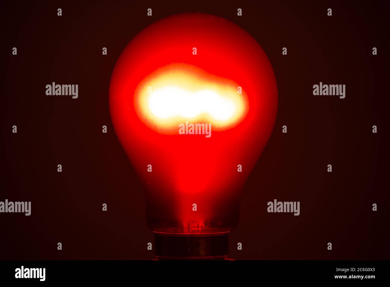 Crompton ruby red tungsten incandescent filament lightbulb lit, red bulb, lightbulb, light, lamp Stock Photo