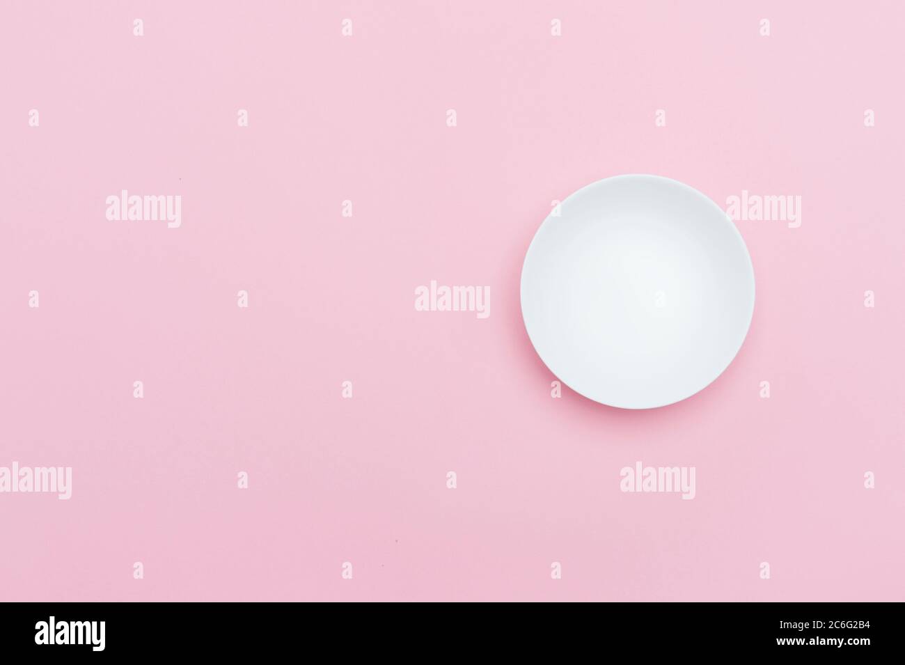 Empty white ceramic round plate isolated on pink Stock Photo