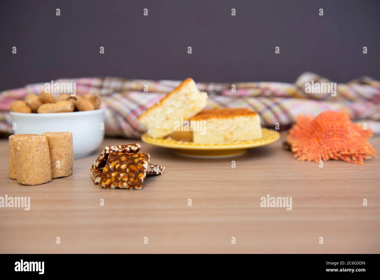 Typical June Party foods on a wooden table: cornmeal cake, peanut pods, peanuts candies (paçoca and pe-de-moloque) and a small country hats. Copy spac Stock Photo