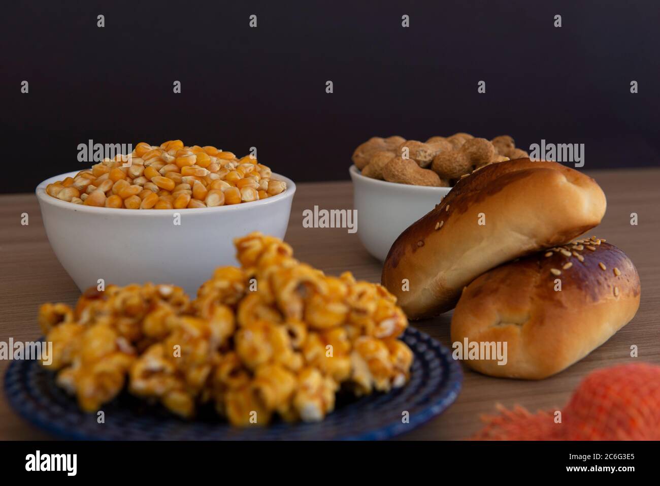 Close up of typical June Party foods on a wooden table: Popcorn, cornmeal cake, corn kernels, peanut pods and small country hats. Copy space. Selectiv Stock Photo