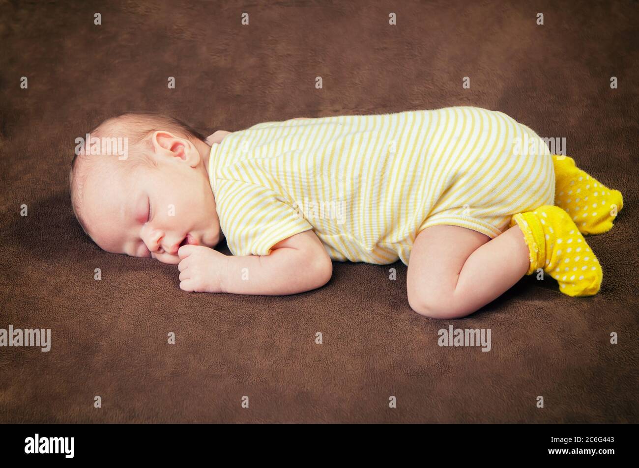 Beautiful newborn baby boy sleeping peacefully on the soft brown blanket Stock Photo