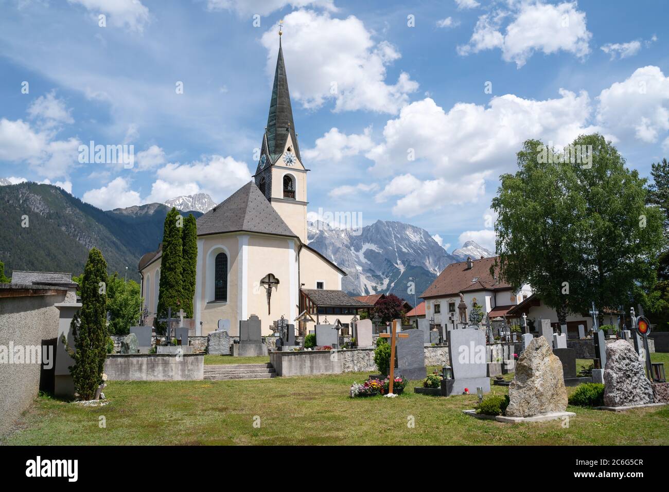 Traditional Austrian village church and cemetery in the sunny alpine mountains, Obsteig, Tirol, Austria Stock Photo