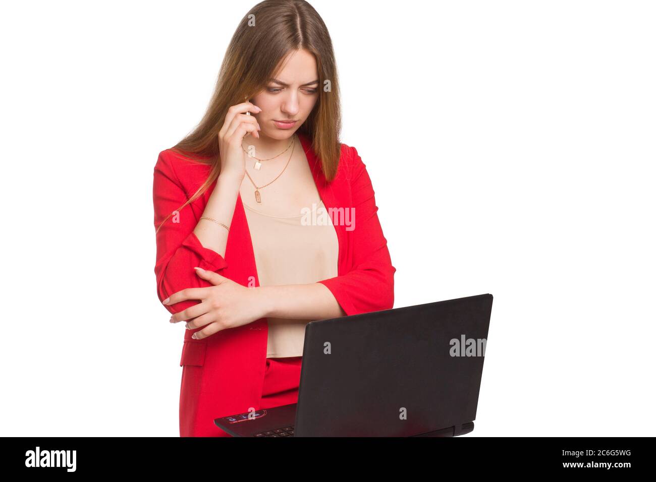 A young business office woman in a red suit a background isolated in white, holding a laptop, and talking on a smartphone Stock Photo