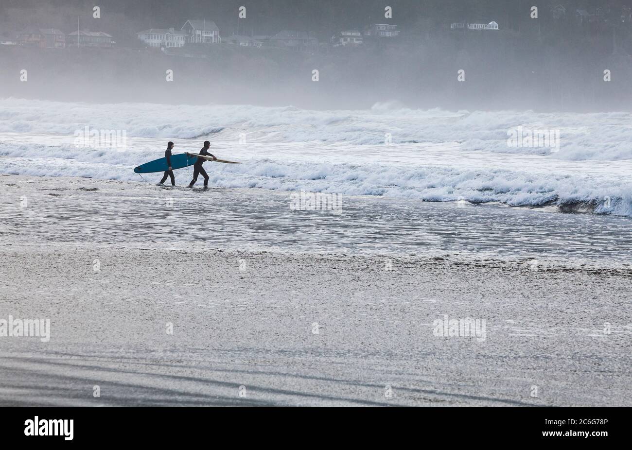 Two young men headed out into the suf with surfboards. Pacific coast, Seaside, Oregon, USA. Stock Photo