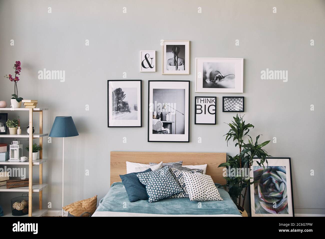 photos of different sizes in a frame hanging over the bed . Modern bedroom interior. Stock Photo