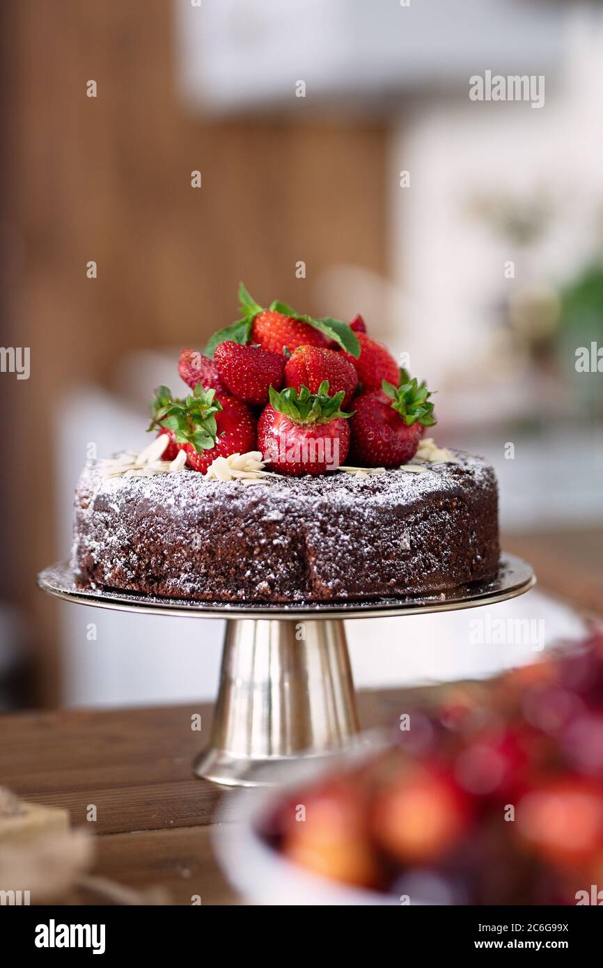 chocolate cake decorated with berries, strawberries lie on  dessert, sweetness lies on metal plate, selective focus Stock Photo