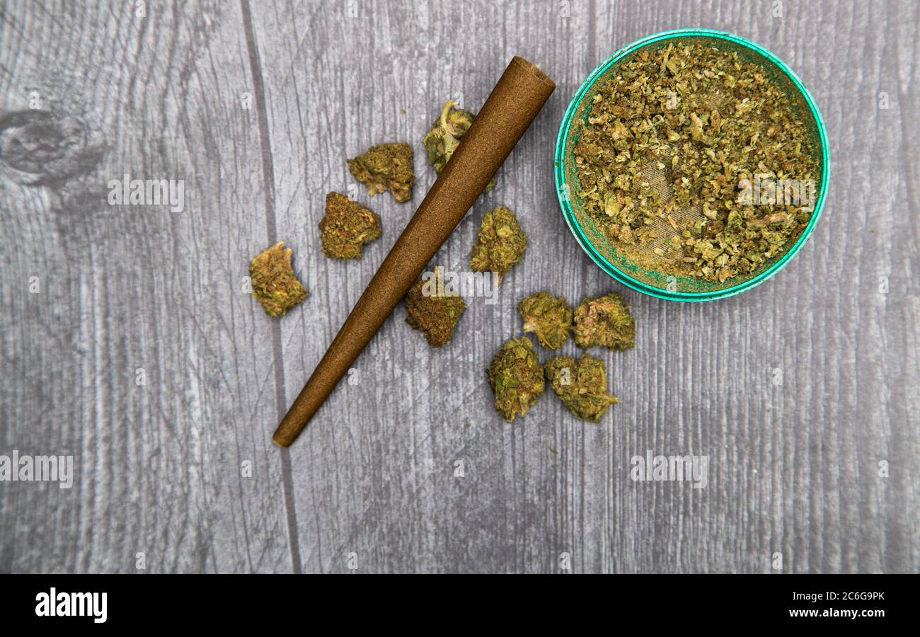 Marijuana buds and joint lie on a dark gray background. Grinder near  cannabis. Marijuana is medicine Stock Photo - Alamy