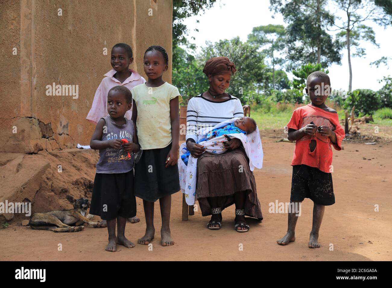 Family, woman, children, baby, sitting in front of mud hut, Uganda, East Africa Stock Photo