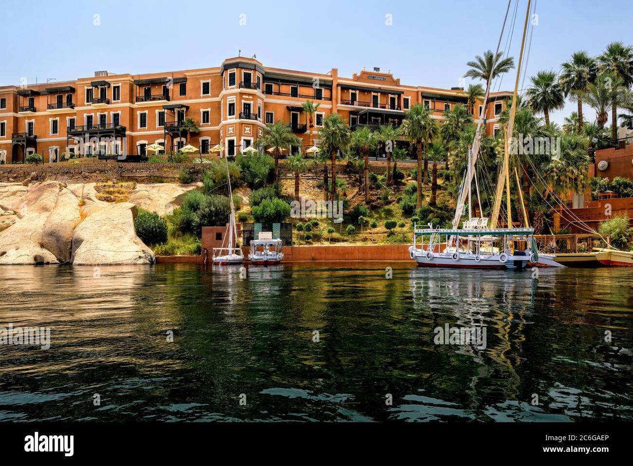 Yachts, Feluccas and Tourist Ferry Boats anchored in front of the Old Cataract Hotel on the Nile River in Aswan Stock Photo