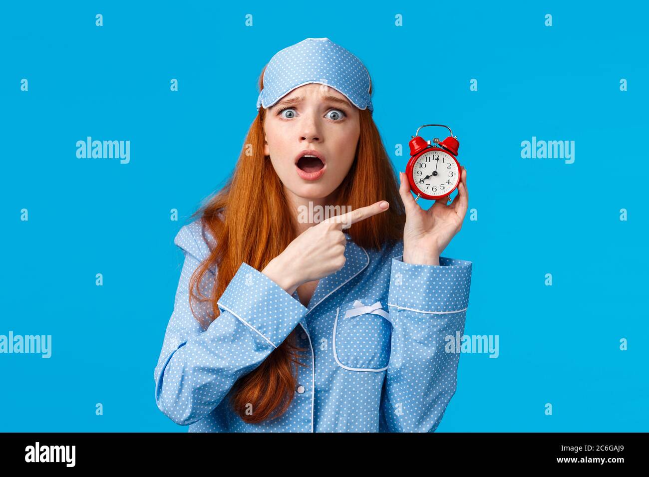 Upset and disappointed gloomy redhead woman in nightwear. sleep mask,  arguing boyfriend didnt set up alarm, pointing at clock wi Stock Photo -  Alamy